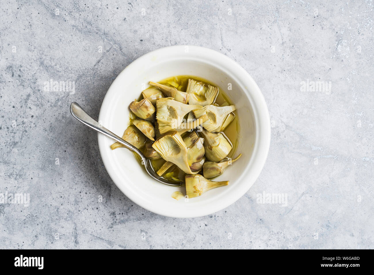 Bowl of cooked baby artichokes on a marble background Stock Photo