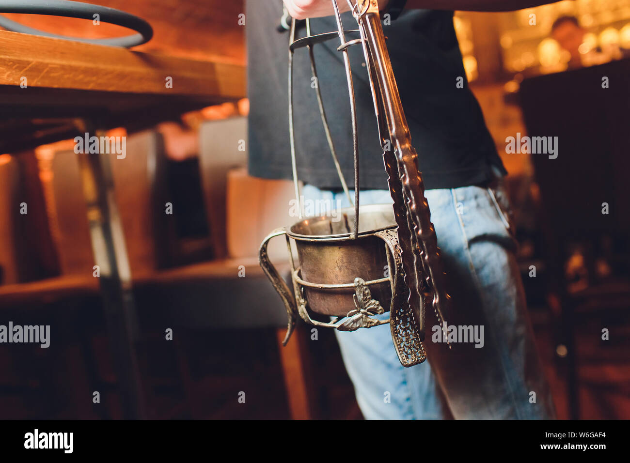 Hookah bowl with coal for smoking closeup. Hands holding forceps for