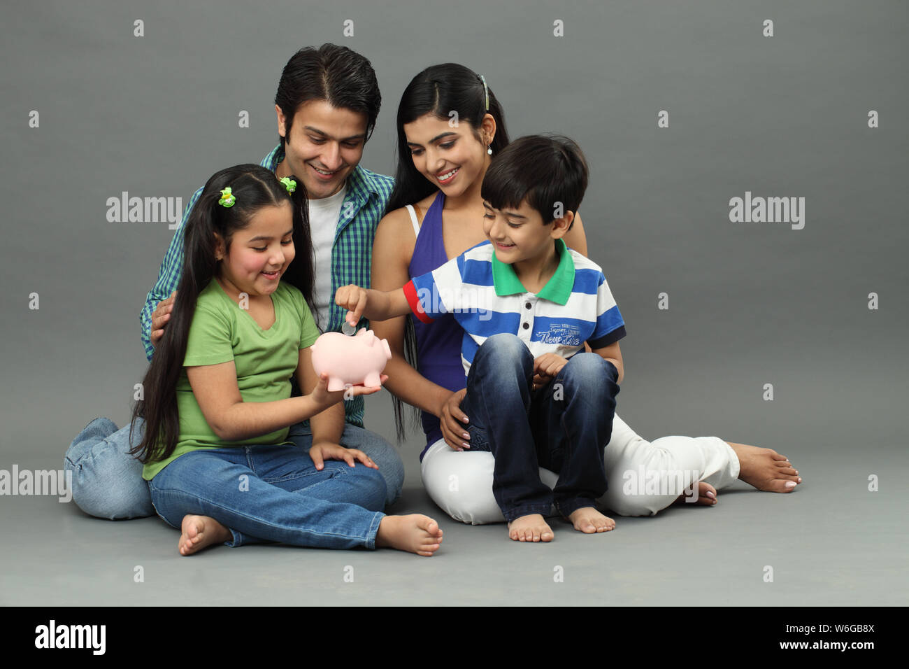 Boy putting coin into a piggy bank with their family Stock Photo - Alamy