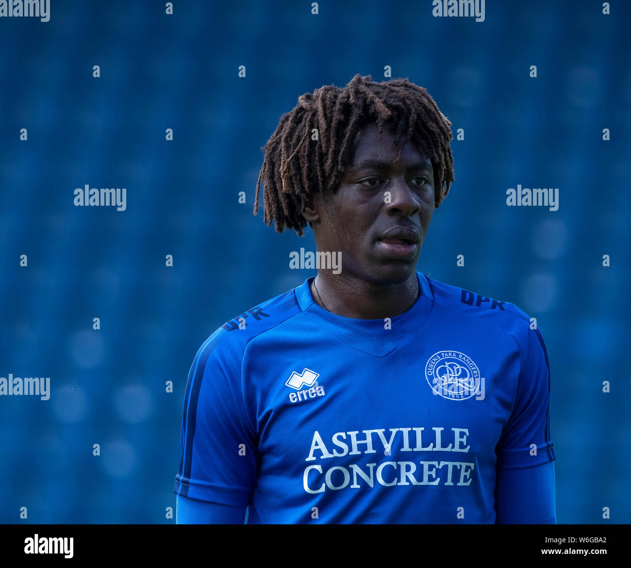 Head and shoulders image of young striker Ebere Eze of Queens Park Rangers FC in blue training kit. Blurred blue seats in the background. Stock Photo