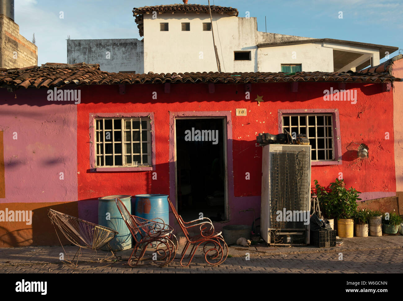 Tile roofed single-storey house with rocking chairs. Authentic street scene in the small island village of Mexcaltitán, Nayarit, Mexico, Jul 2019 Stock Photo