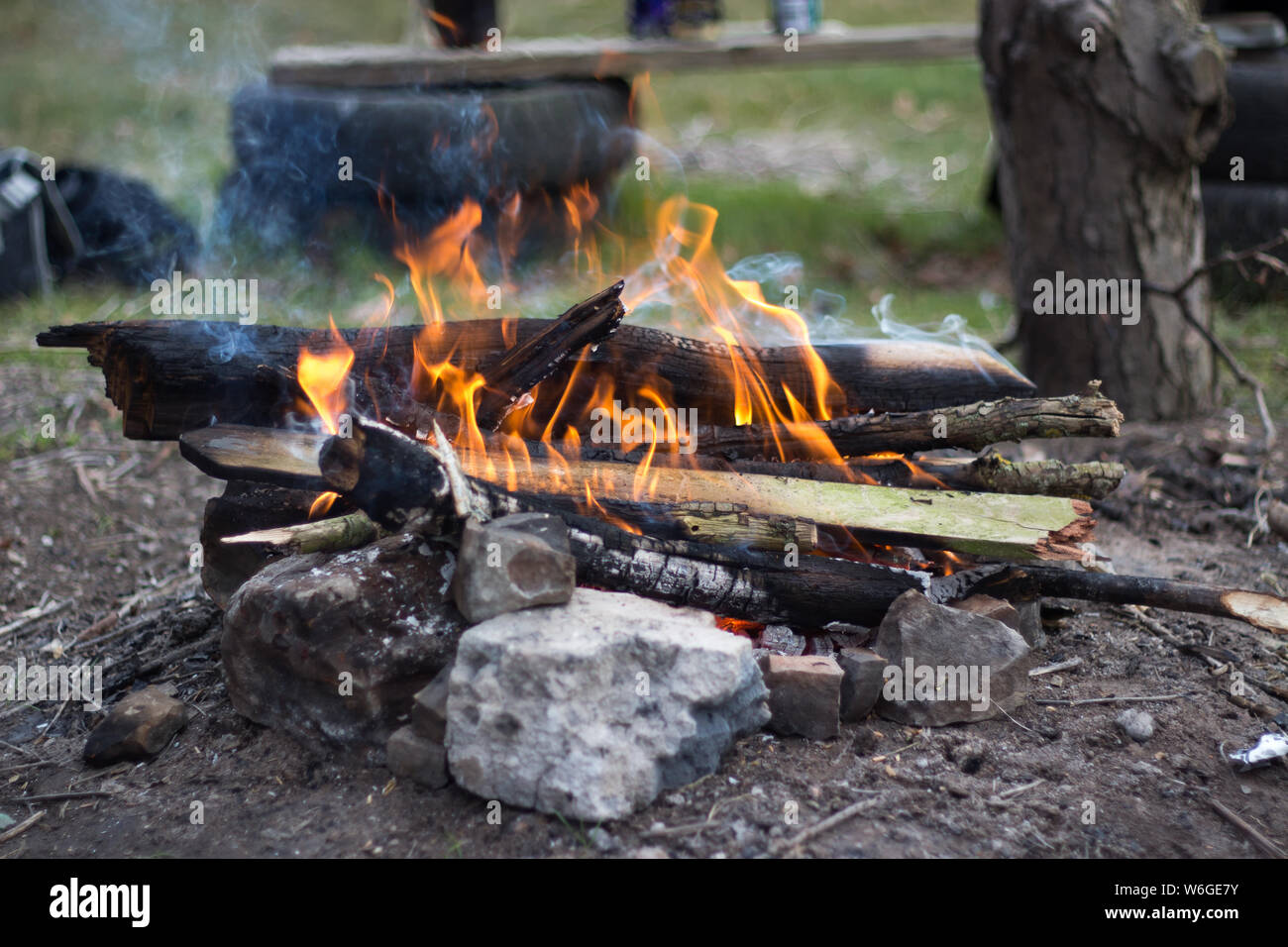 A small campfire made up of twigs and branches with rocks surrounding ...