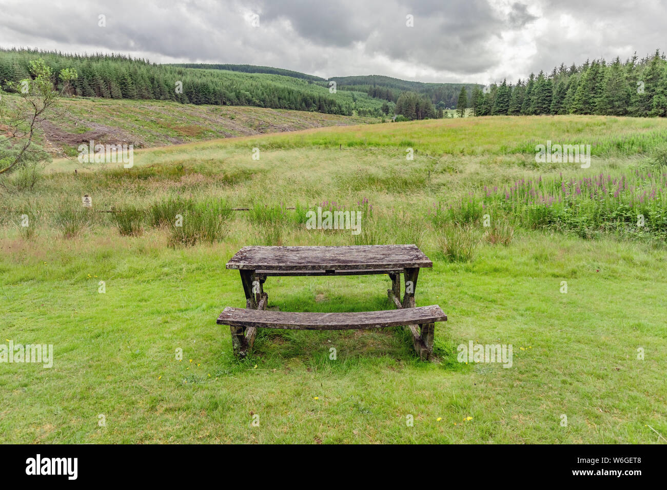 Isolated park bench in the countryside in mid-Wales, with a view of a stormy sky Stock Photo