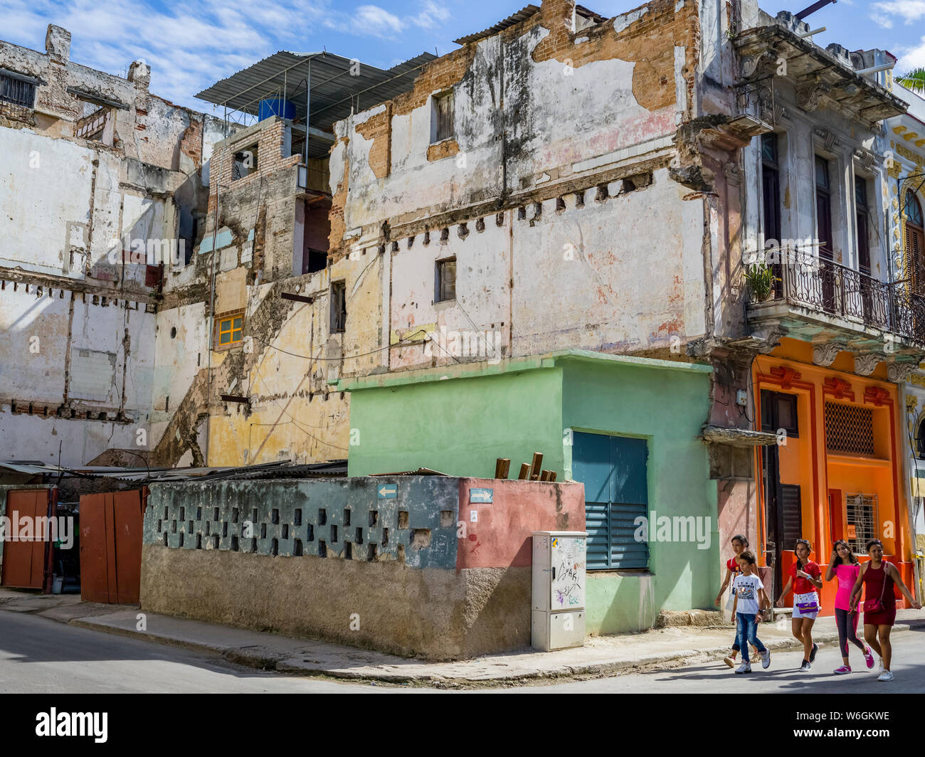Pedestrians walk on the street past a run-down building; Havana, Cuba Stock Photo