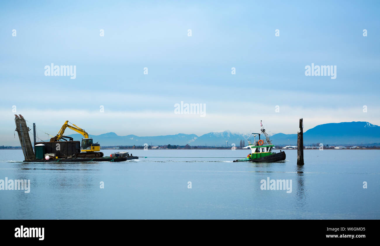 Tugboat pulling barge with construction equipment, Blackie Spit, Crescent Beach; Surrey, British Columbia, Canada Stock Photo