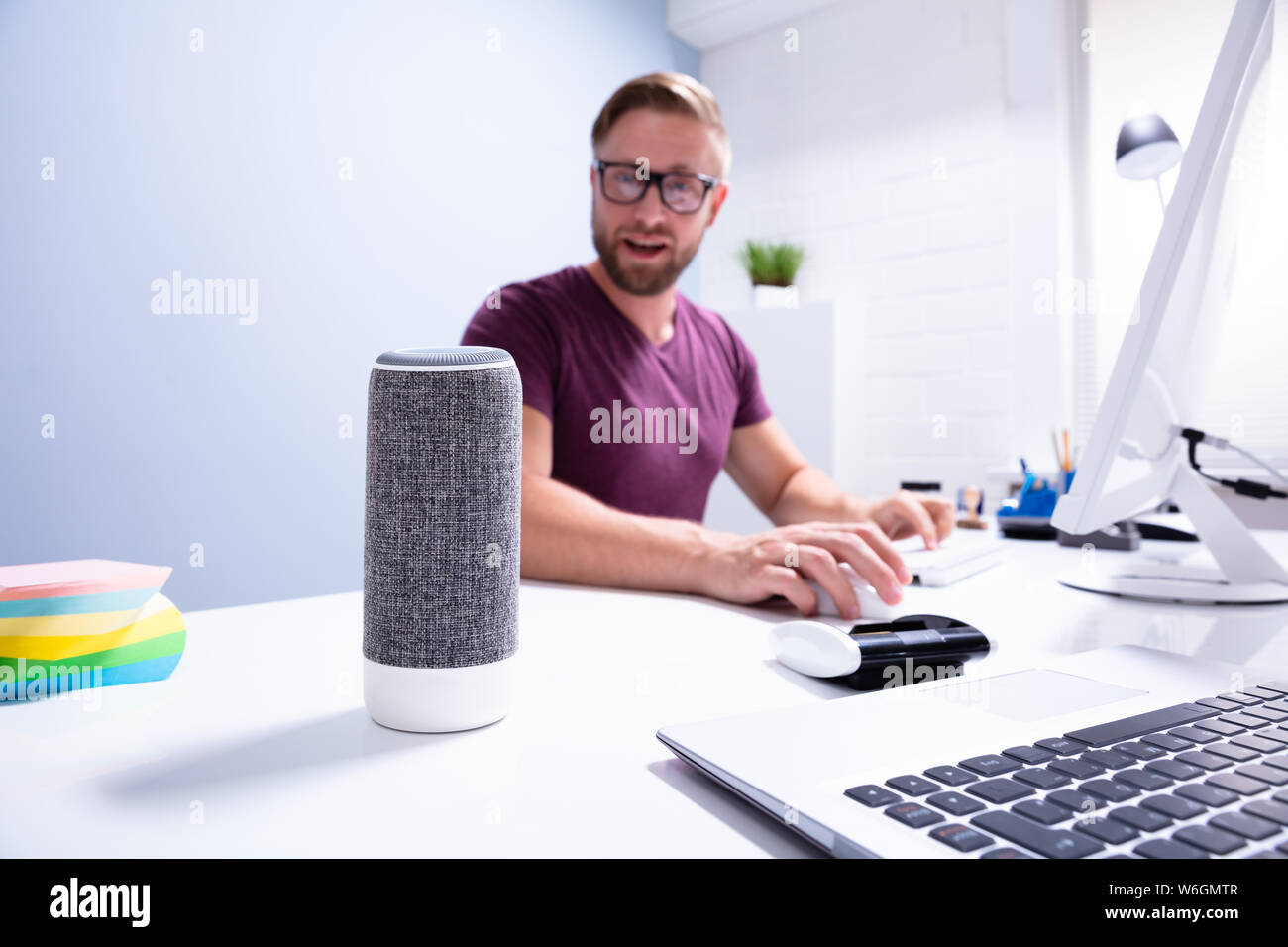 Young Man Working In Office Looking At Wireless Speaker Stock Photo