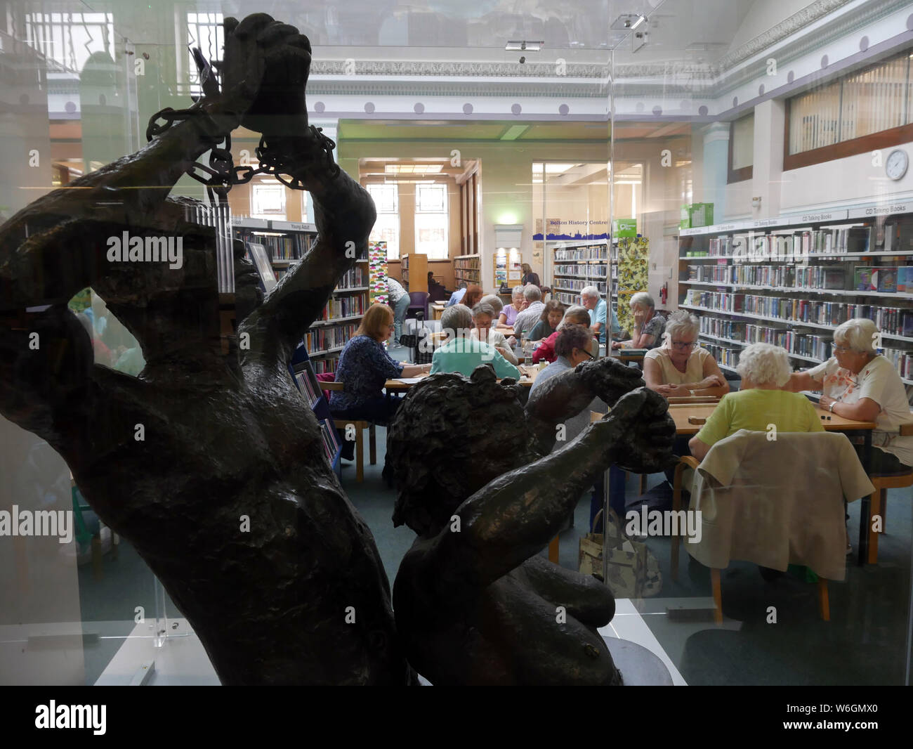 “Study for Slave Hold” a cased Cast bronze sculpture by Jacob Epstein   in the background a Mah-Jong Club is playing the aincient Chinese game. Stock Photo
