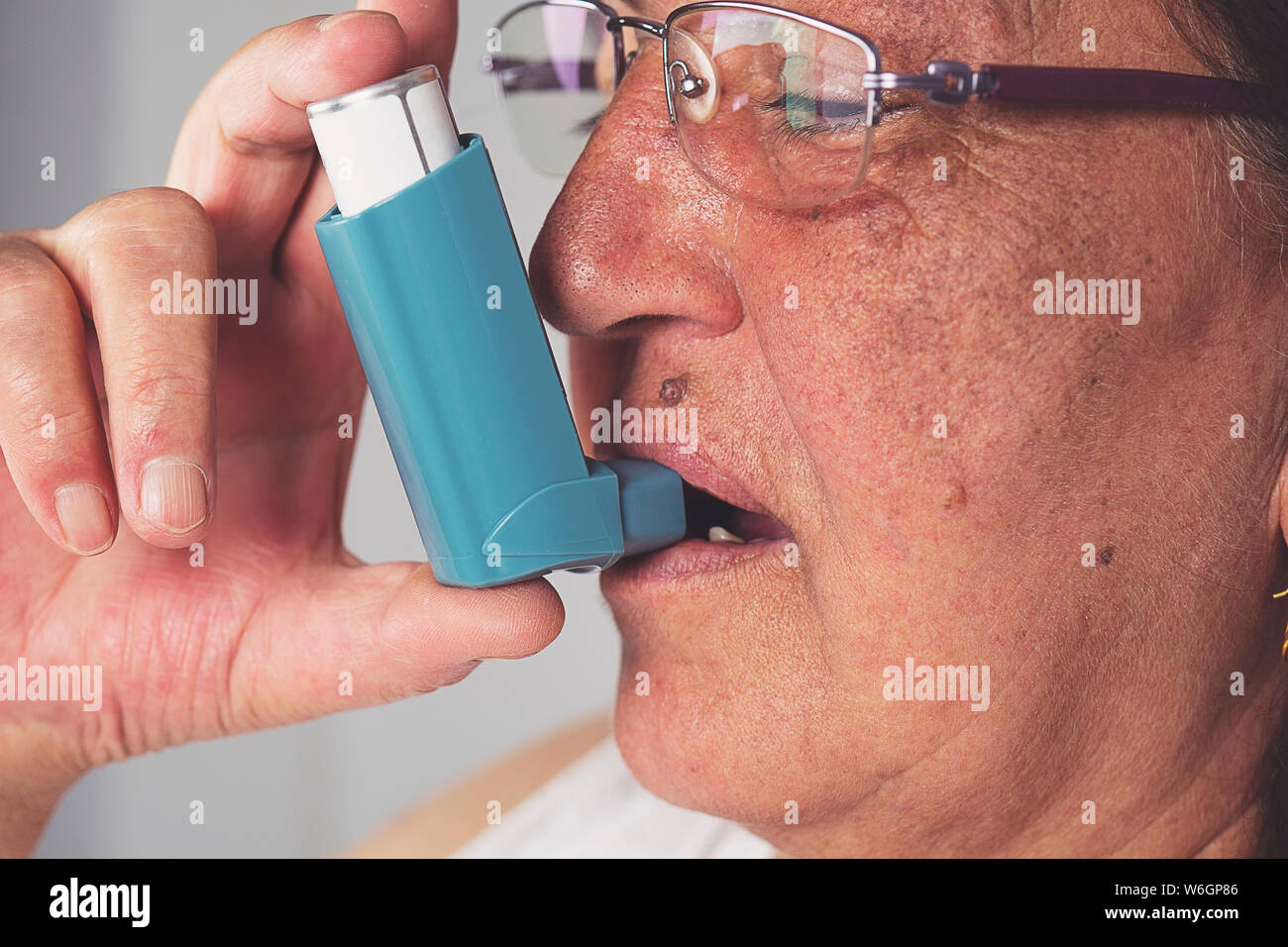 Old woman using asthma inhaler. Asthma Treatment, Elderly Person Stock