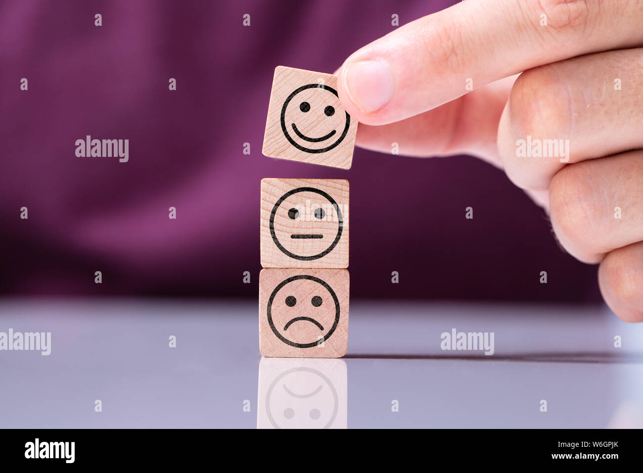 Person Stacking Smiling Cube On Top Of Other Wooden Cubes Stock Photo