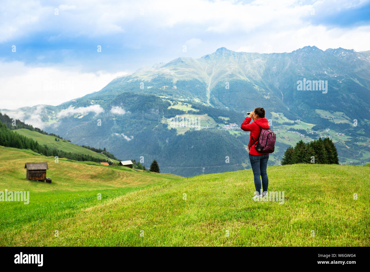 Woman With Backpack In Mountains Looking In Spyglass Stock Photo