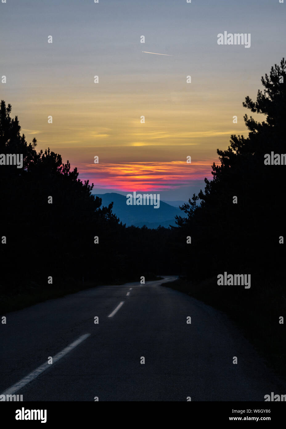 Mountain road leading into the sunset. Graphical image with simple ...