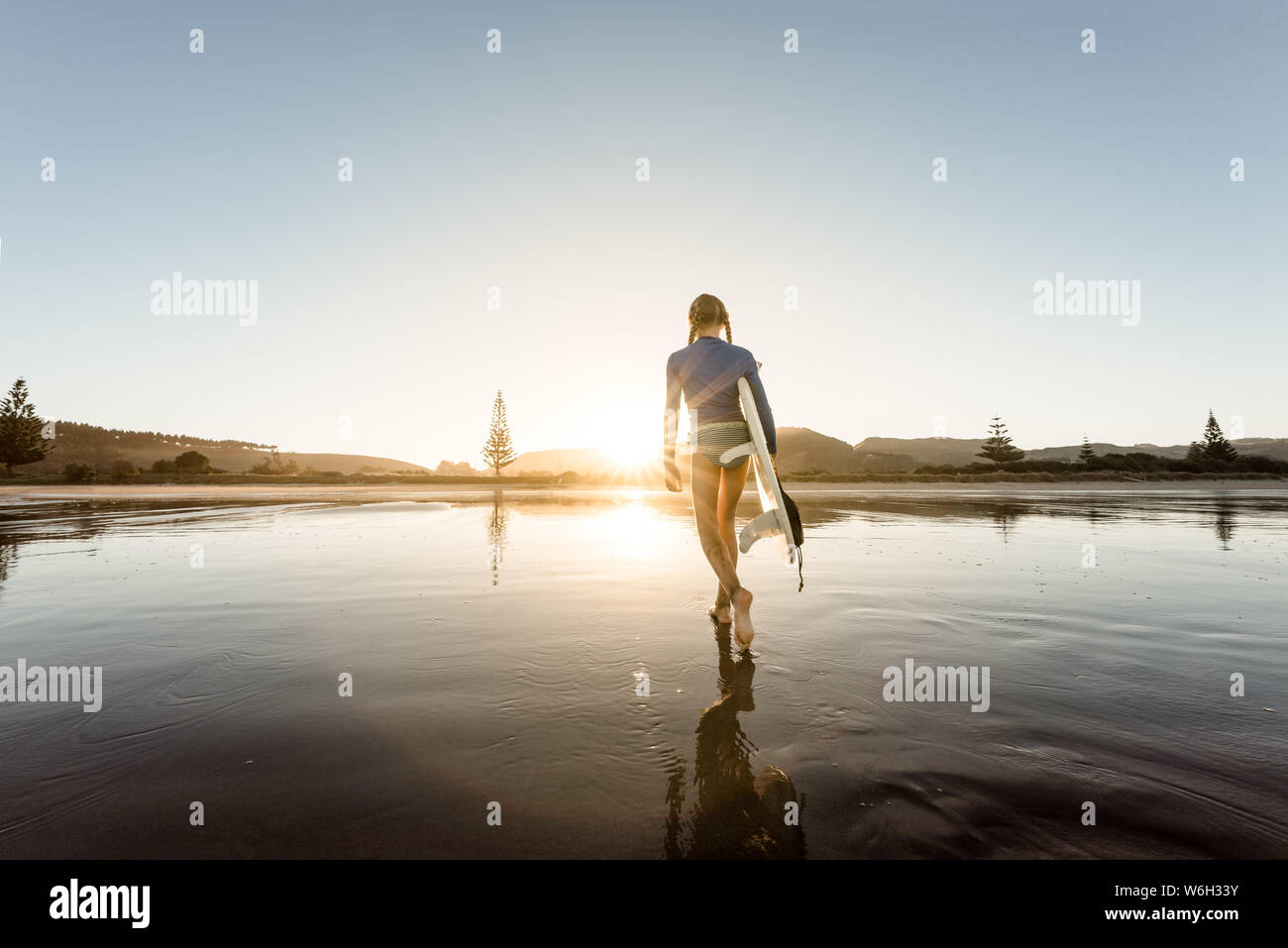Young female carrying surfboard at beach Stock Photo - Alamy