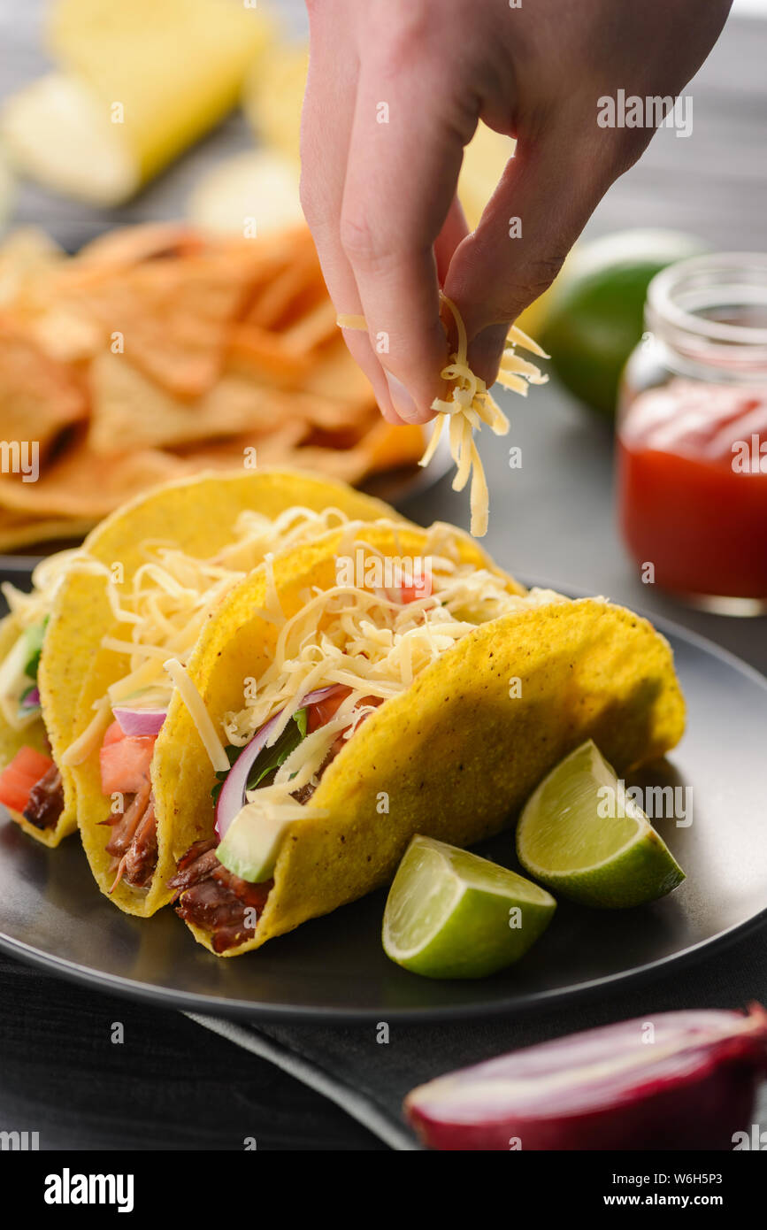 Hand sprinkles cheese onto tacos Stock Photo - Alamy, image size:867x1390