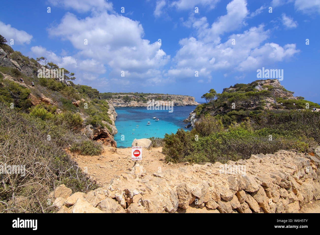 CALO DES MORO, MALLORCA, SPAIN - JULY 27, 2019: Danger sign by small extremely turquoise bay and steep cliffs on a sunny day on July 27, 2019 in Calo Stock Photo