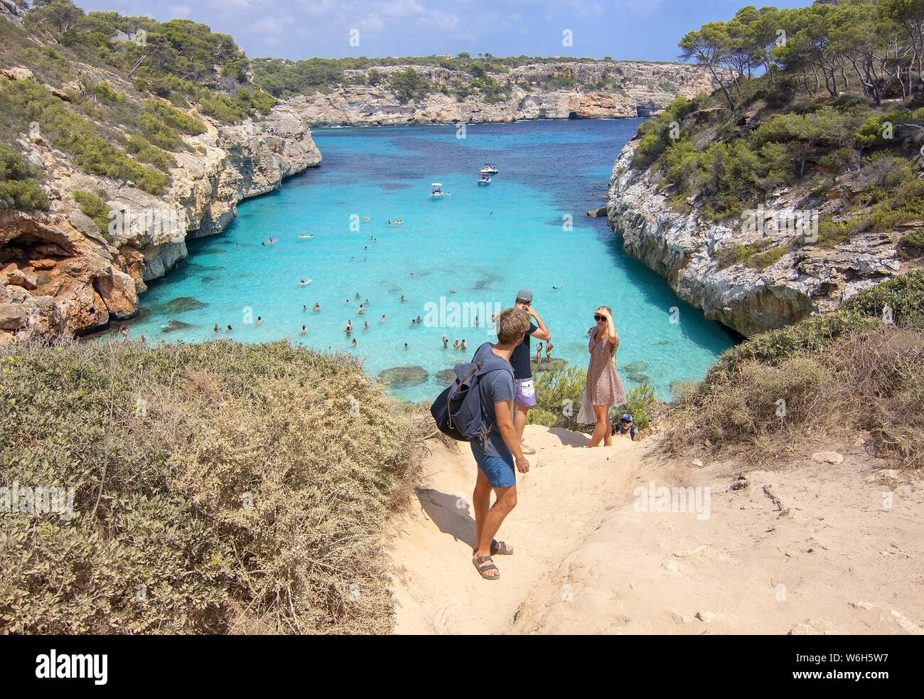 CALO DES MORO, MALLORCA, SPAIN - JULY 27, 2019: People hesitant to walk down to small extremely turquoise bay and steep cliffs on a sunny day on July Stock Photo