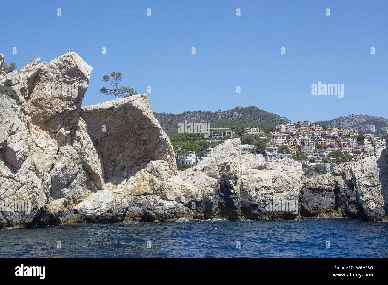 Coastal rocks and village in the distance in southwest Mallorca, Spain. Stock Photo