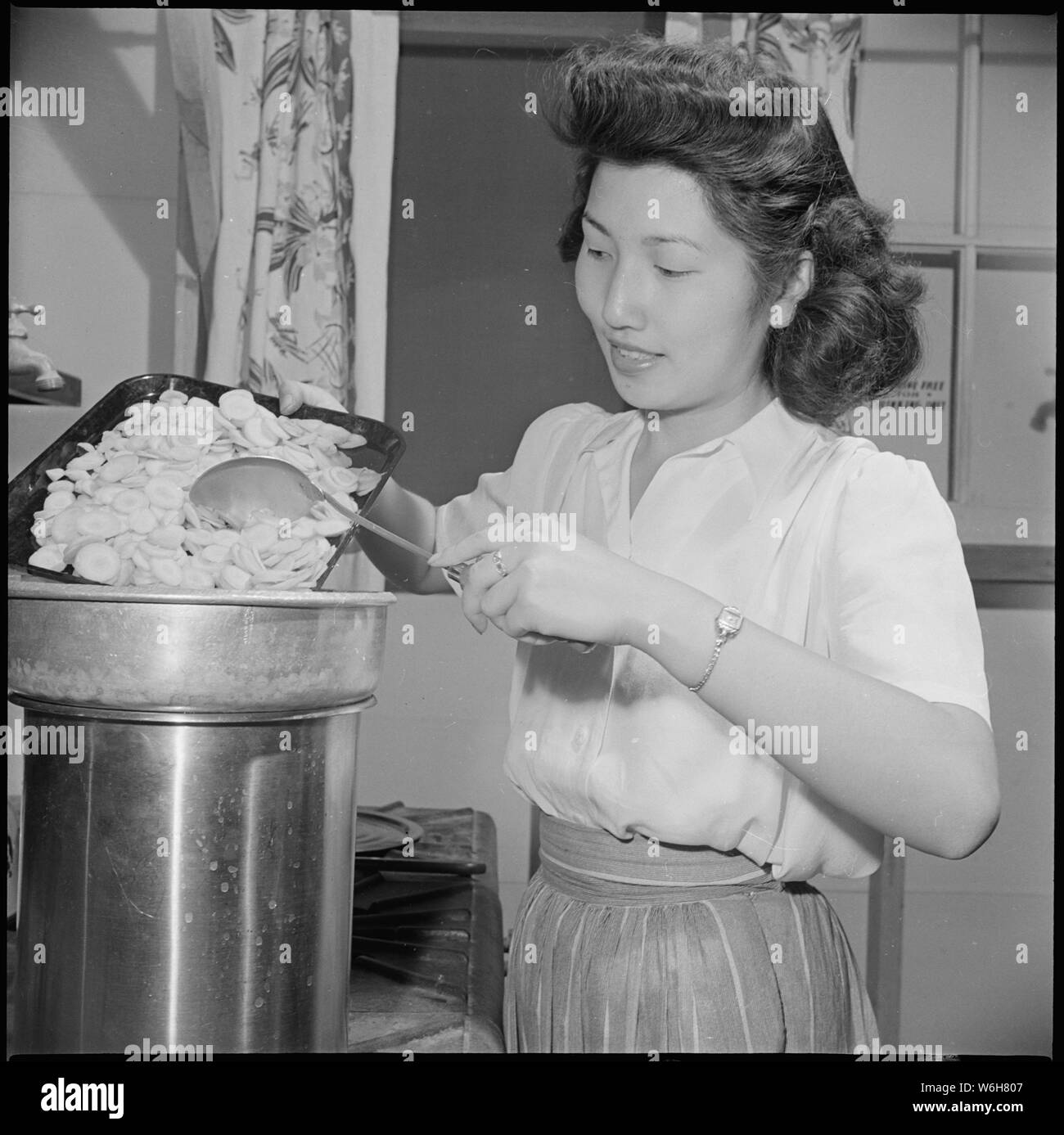 Gila River Relocation Center, Rivers, Arizona. Student Mary Sakai, former resident of Stockton, Cal . . .; Scope and content:  The full caption for this photograph reads: Gila River Relocation Center, Rivers, Arizona. Student Mary Sakai, former resident of Stockton, Califronia, is shown putting sliced carrots in a double boiler in preparation for the drying process. Stock Photo