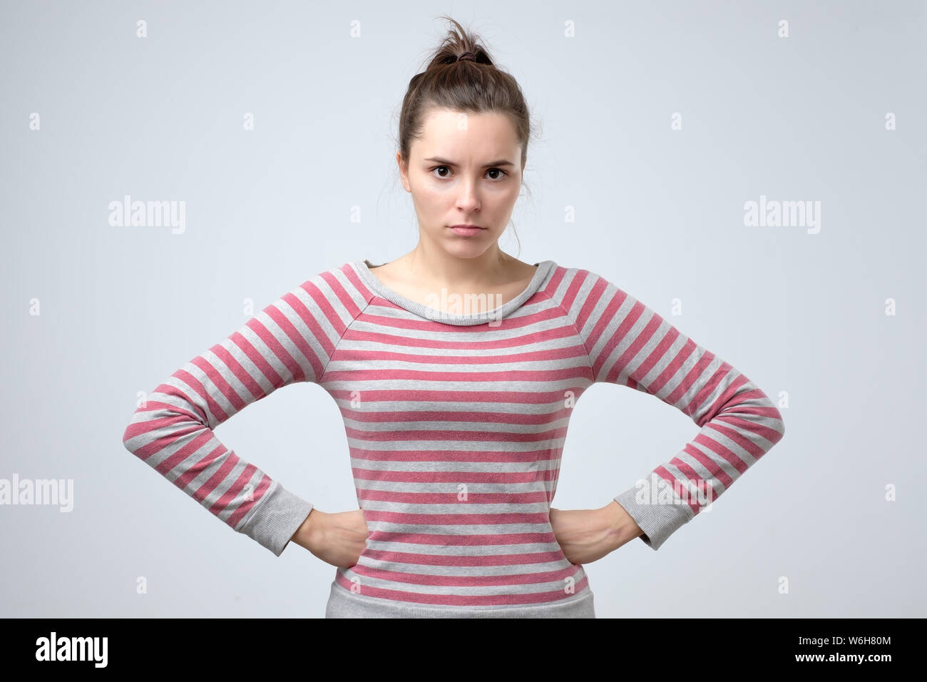 Displeased angry teenager holding hands on hips, frowning Stock Photo