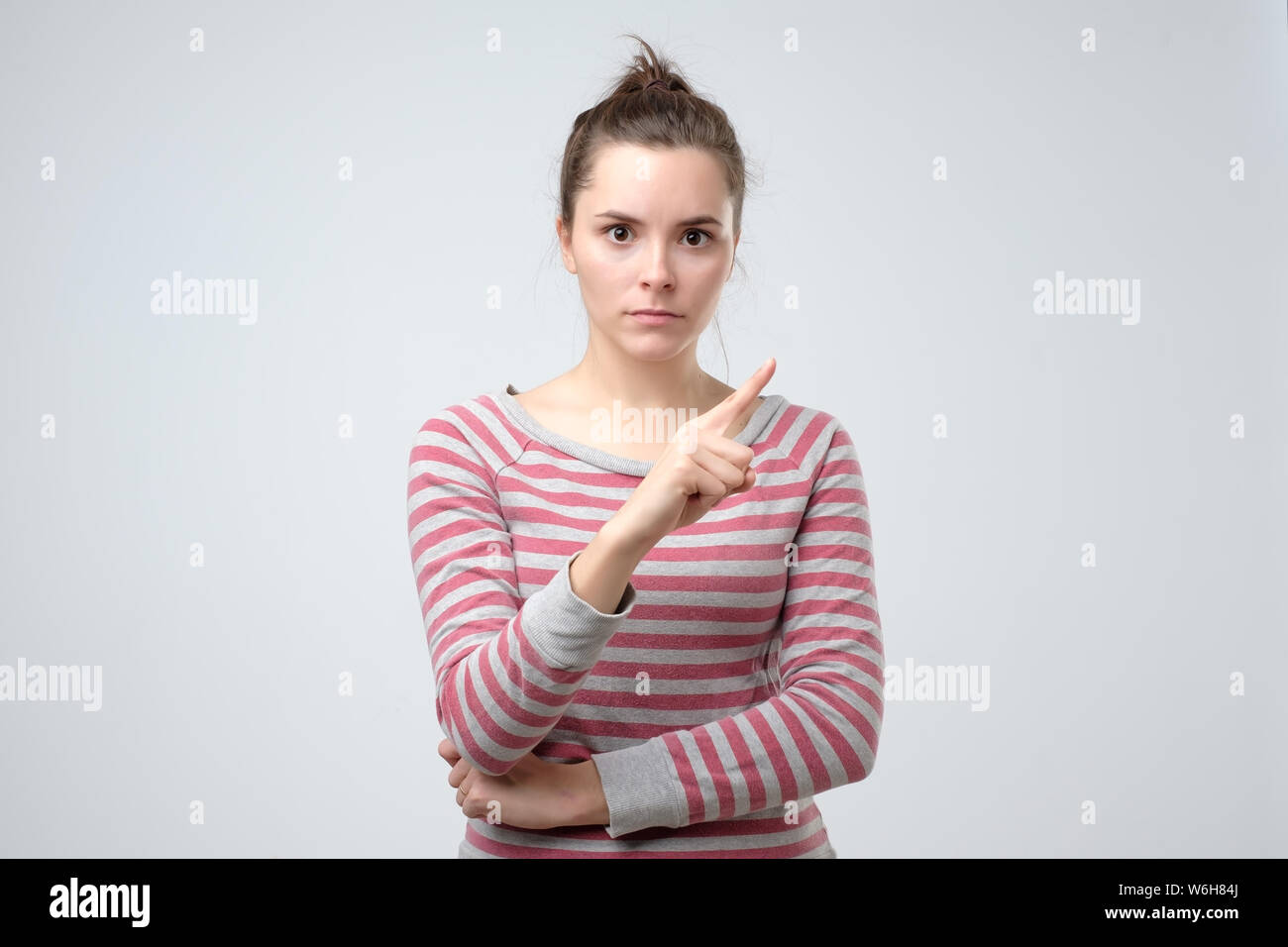 Young woman looks stressed and pointing up with finger saying no Stock Photo
