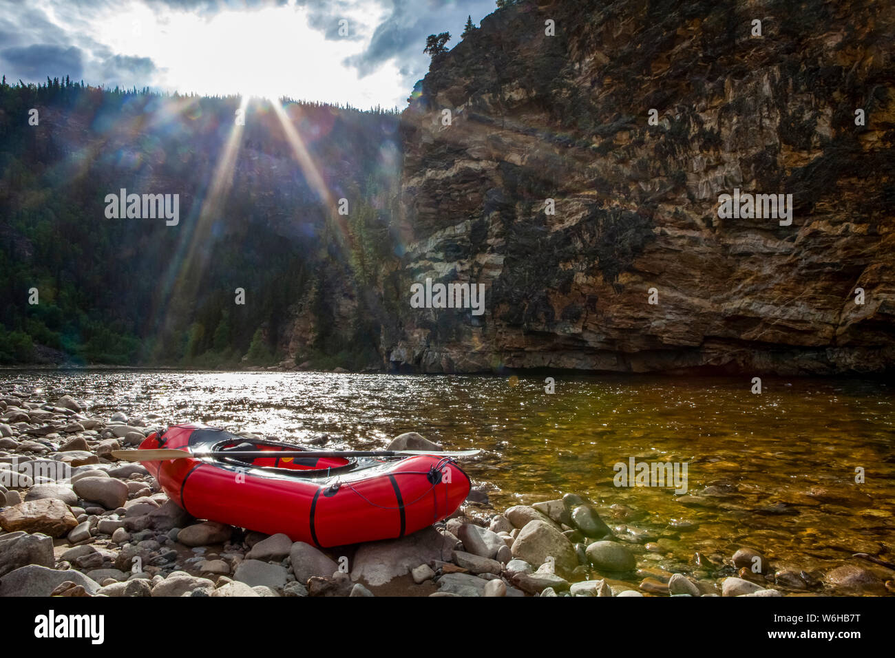 Packraft on the banks of the Charley River, sun going down behind ridge in background, Yukon-Charley Rivers National Preserve Stock Photo