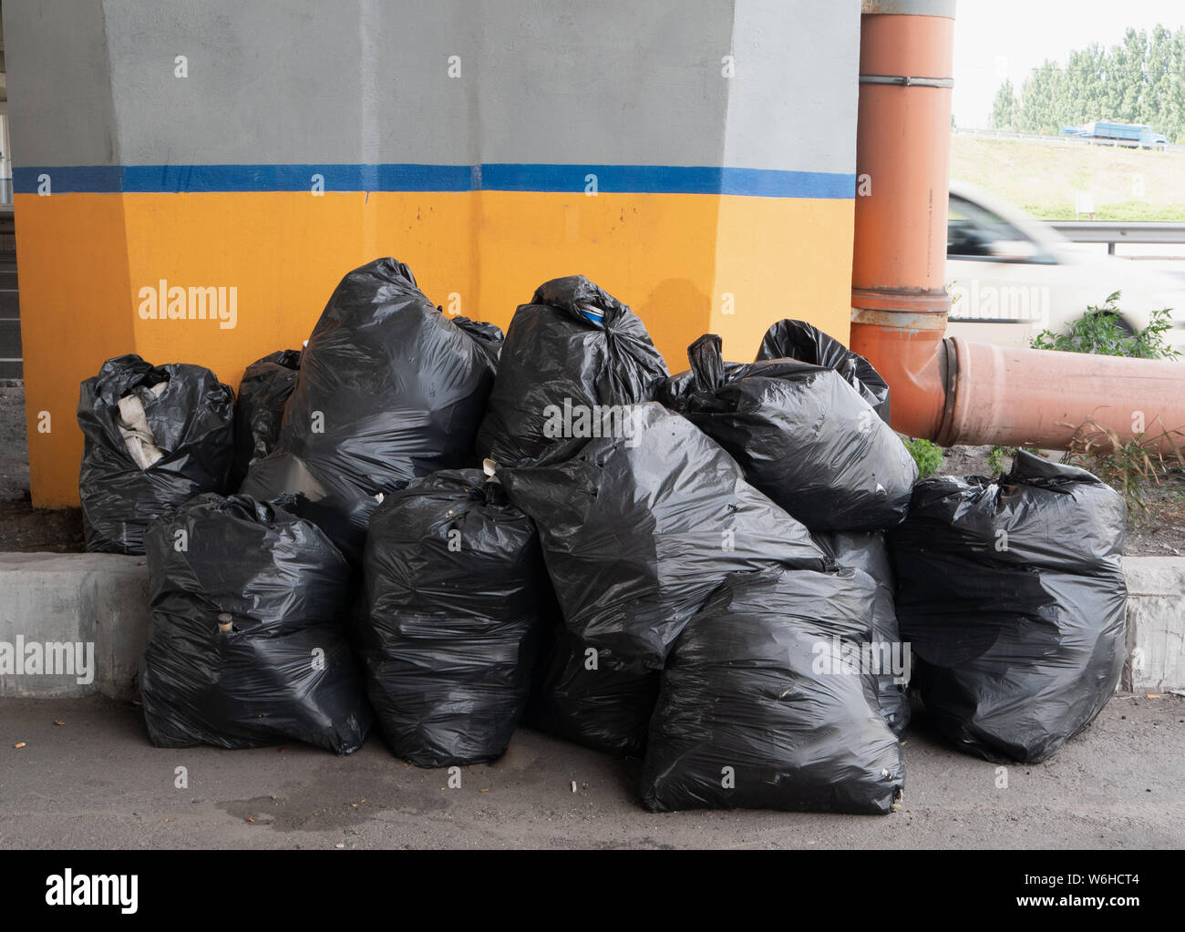 heap of black trash bags on city street waiting for delivery to