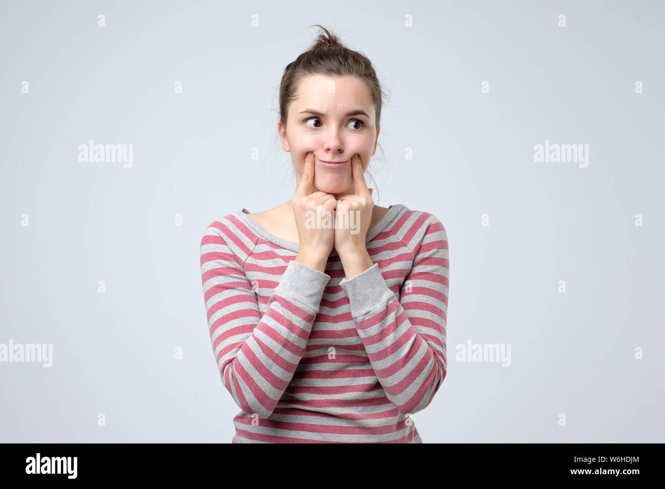 Woman making fake smile with her fingers stretching the corners of her mouth Stock Photo