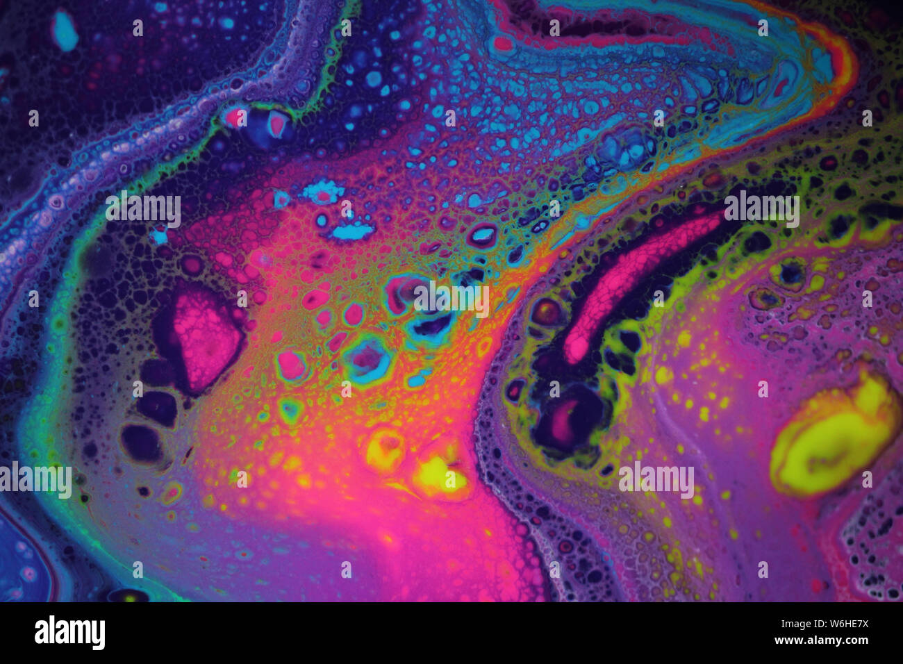 Abstract acrylic pour painting in vibrant neons with cosmic feel for use as background. Stock Photo
