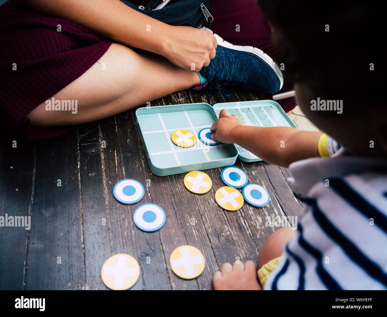 Little boy playing noughts and crosses on a wooden bench Stock Photo