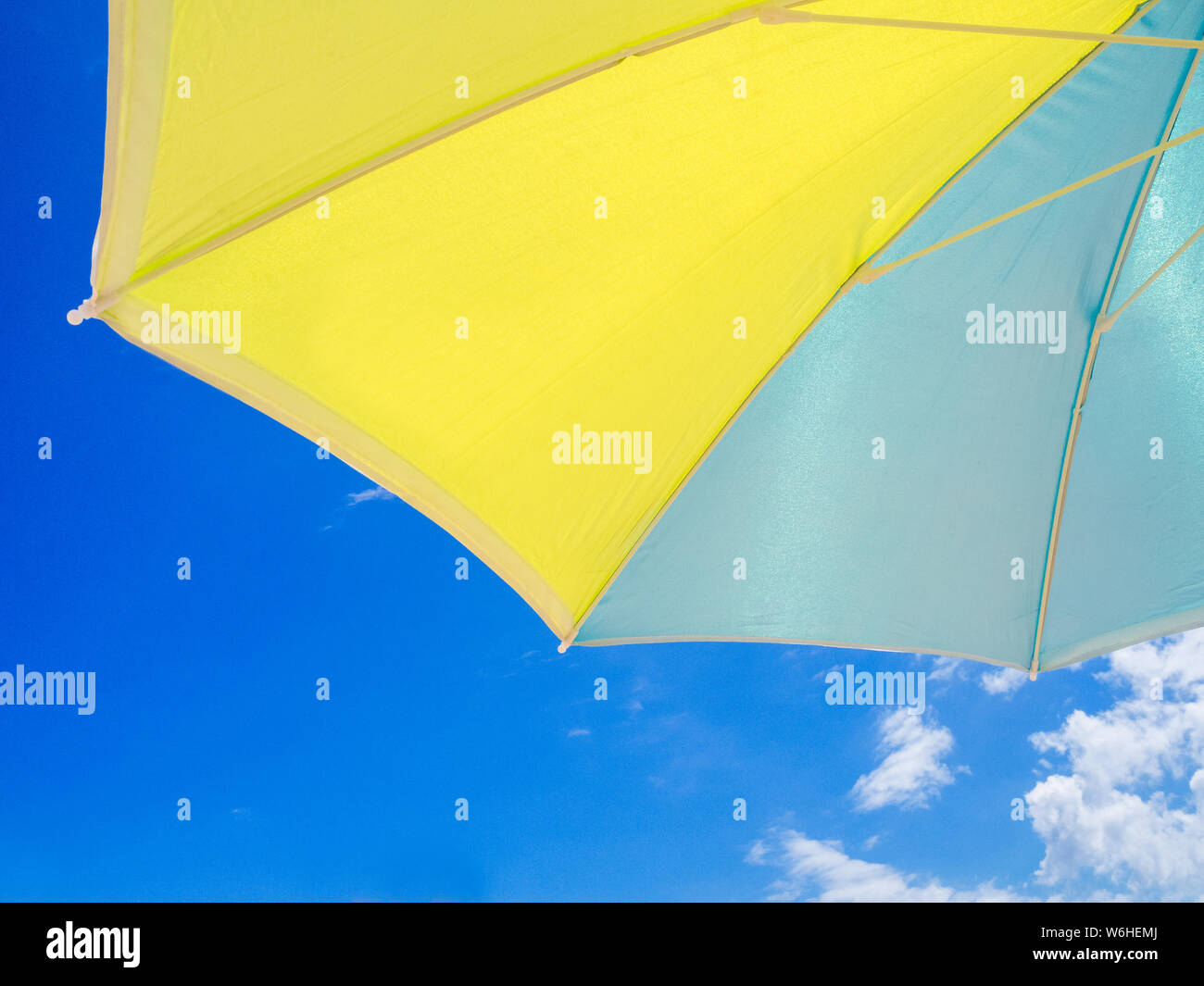 blue and yellow parasol seen from below with the sky behind Stock Photo