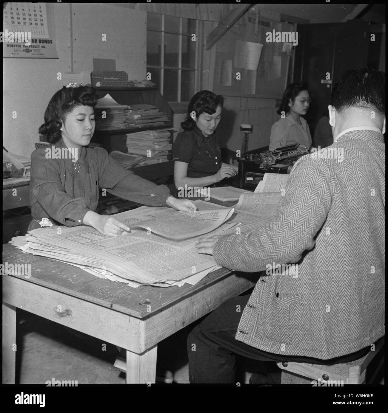 Heart Mountain Relocation Center, Heart Mountain, Wyoming. The repertorial staff of the Sentinel, H . . .; Scope and content:  The full caption for this photograph reads: Heart Mountain Relocation Center, Heart Mountain, Wyoming. The repertorial staff of the Sentinel, Heart Mountain Relocation Center newspaper do double duty on Friday night and Saturday morning in folding and preparing their paper for distribution. The paper, edited and published without War Relocation Authority censorship, represents the news and expresses the views of residents of Japanese ancestry relocated from west coast Stock Photo