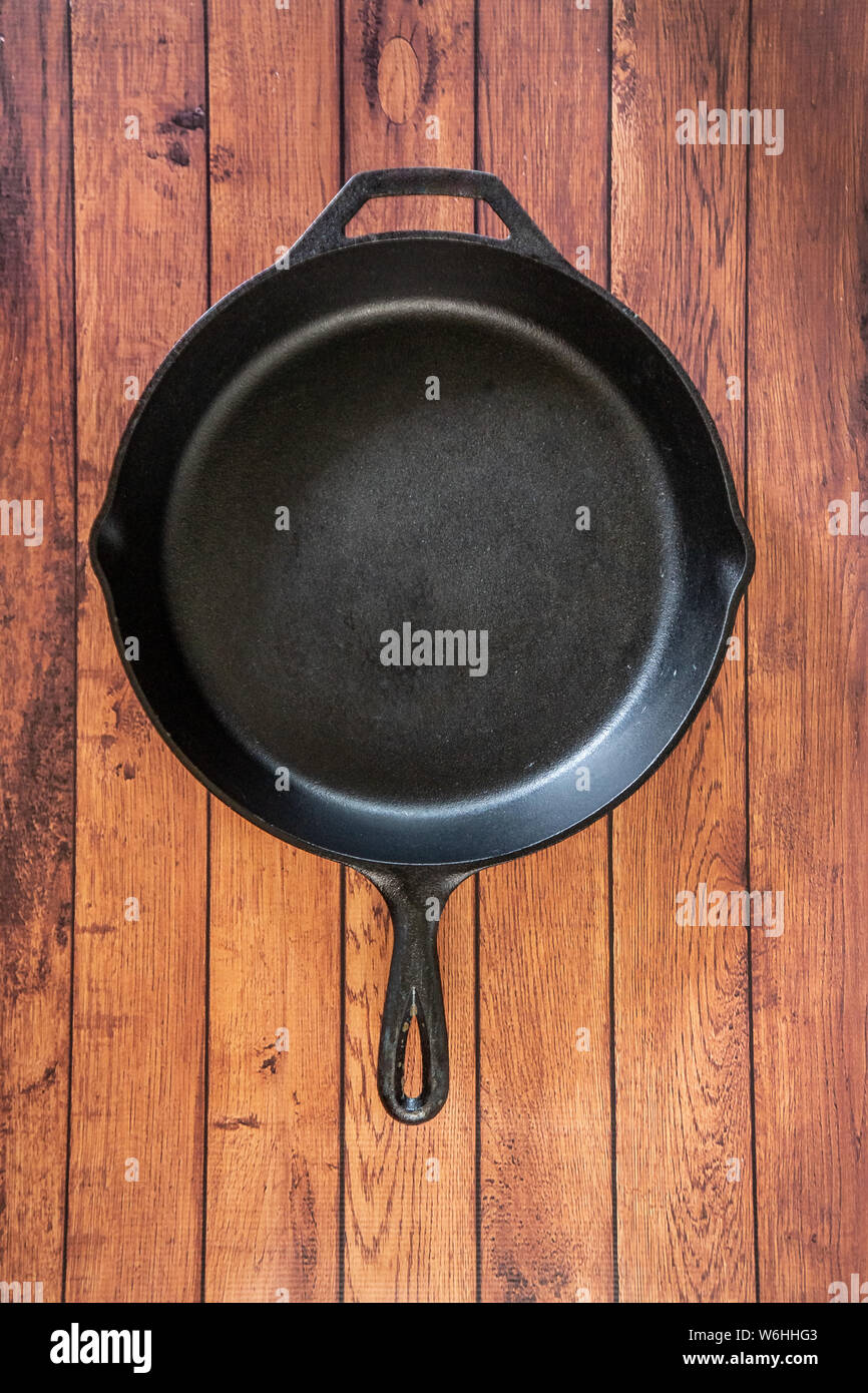 Traditional heavy duty cast iron skillet on wooden surface isolated