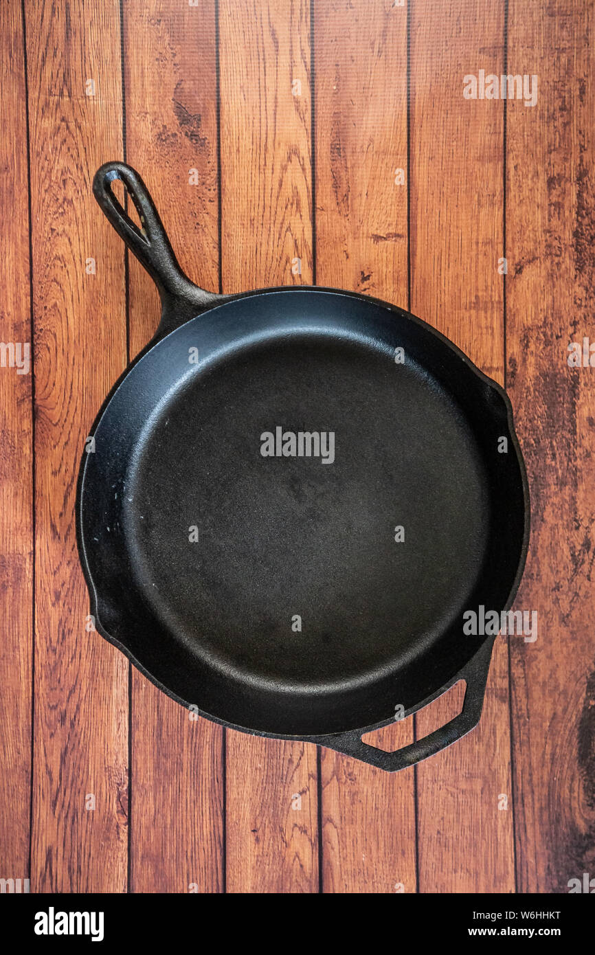 Traditional heavy duty cast iron skillet on wooden surface isolated