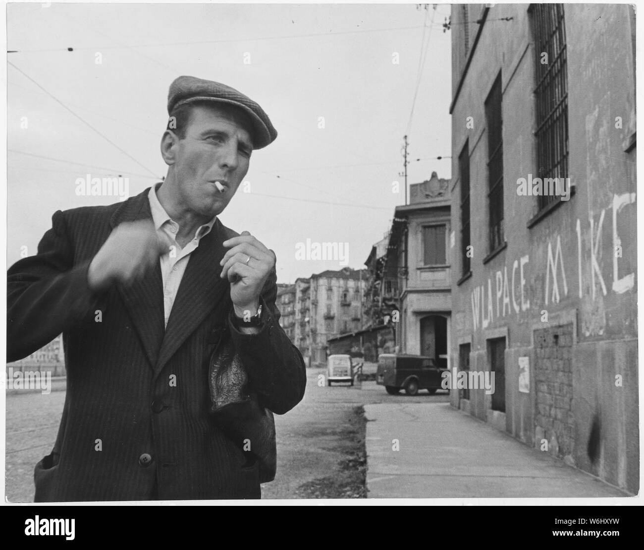 Italy. [A man smoking a cigarette. On the wall the inscription reads Up  with peace, down with Ike (Eisenhower)] Stock Photo