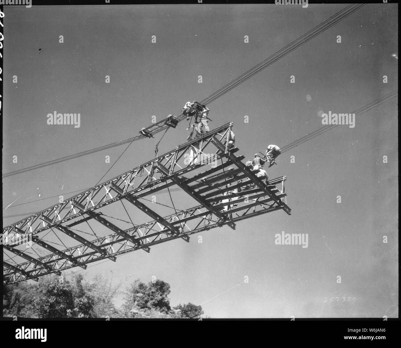 Looking up from Taiping River as cables are attached to suspension clamps of stiffening girder section from west bank, in order to raise or lower it to level of section from opposite bank. Bailey bridge. 209th Engr. Combat Battalion China, February 4, 1945.; General notes:  Use War and Conflict Number 862 when ordering a reproduction or requesting information about this image. Stock Photo