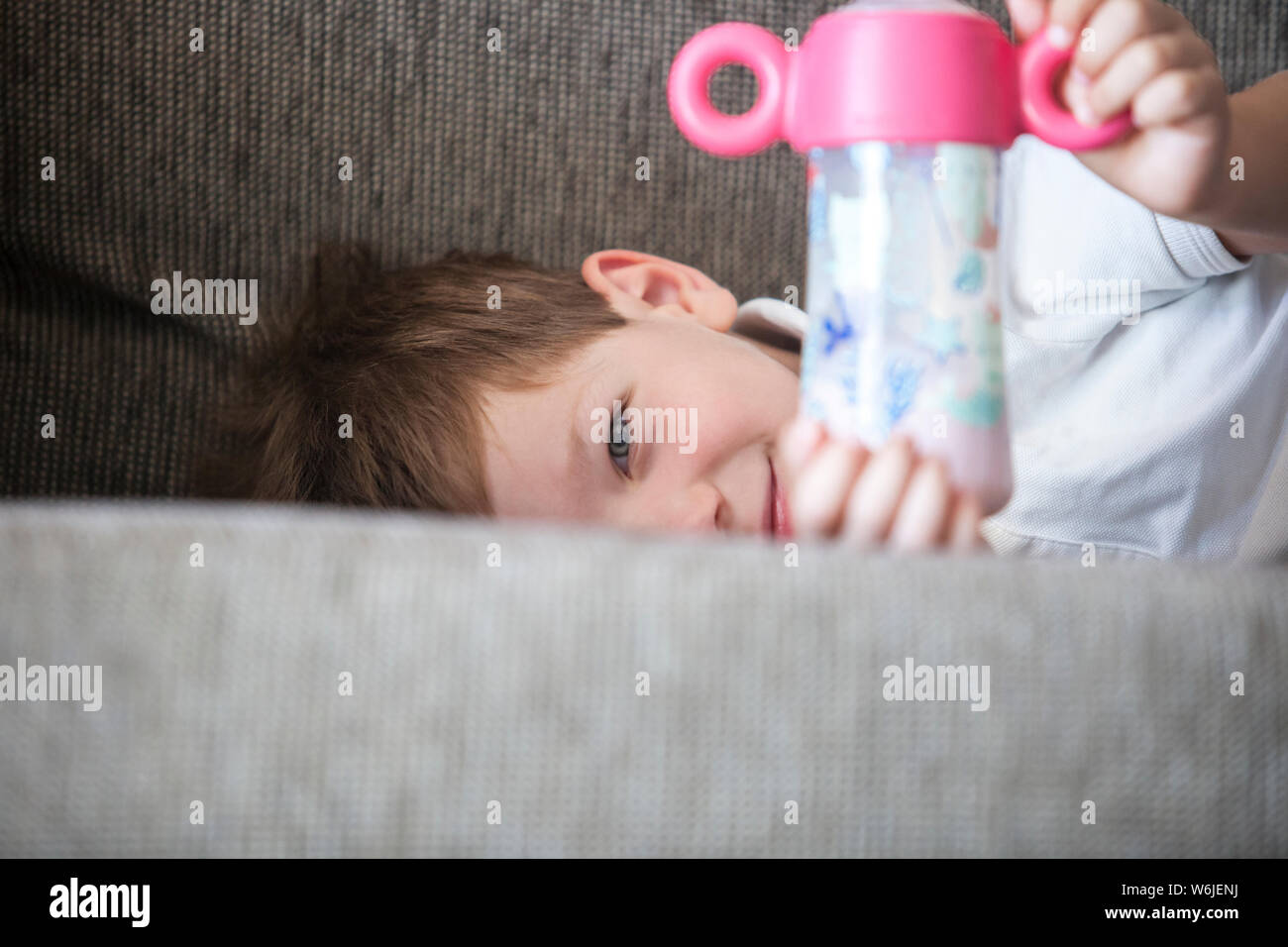 Smiling 4 years boy drinking with baby bottle. Stop using baby bottle