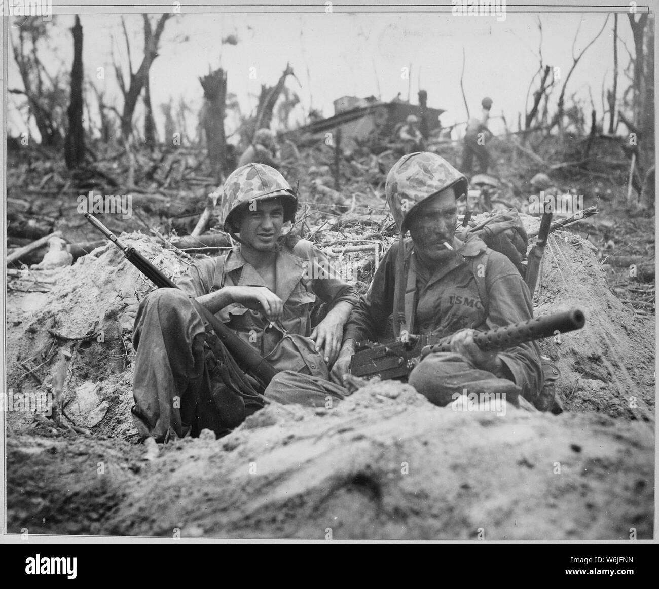 Marine Private First Class Douglas Lightheart (right) cradles a 30-caliber machine gun in his lap, while he and his buddy Private First Class Gerald Churchby take time out for a cigarette, while mopping up the enemy on Peleliu Islands; General notes:  Use War and Conflict Number 874 when ordering a reproduction or requesting information about this image.The Marine on the left has been tentatively identified through information received by the National Archives as being Gerald P. Thursby, Sr. of Akron, Ohio, not Gerald Churchby. Stock Photo