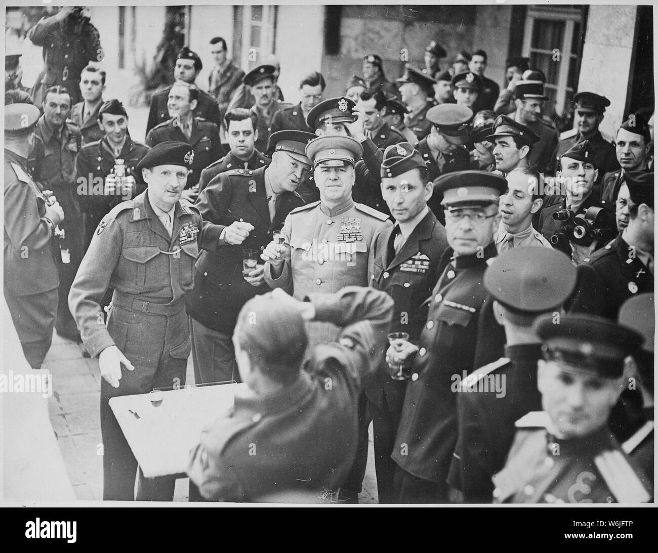 Marshal Zhukov decorates Field Marshal Montgomery with the Russian Order of Victory. Allied chiefs who attended the ceremony at Gen. Eisenhower's Headquarters at Frankfurt are about to drink a toast. British Official.; General notes:  Use War and Conflict Number 1097 when ordering a reproduction or requesting information about this image. Stock Photo