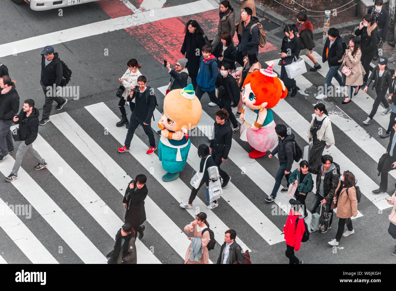 Shibuya crossing, crowds at intersection, many pedestrians and Japanese mascots cross zebra crossing, Shibuya, Udagawacho, Tokyo, Japan Stock Photo