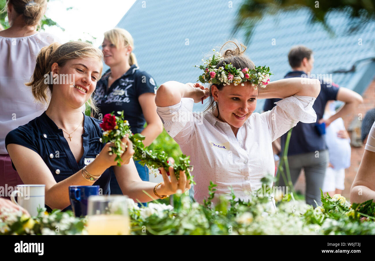 Hoopte, Germany. 10th July, 2019. Teresa-Marie Pelka (r), of the young countrywomen ties a wreath of flowers with Maria Klöss (l). The number of rural women in Lower Saxony is growing steadily. Credit: Philipp Schulze/dpa/Alamy Live News Stock Photo