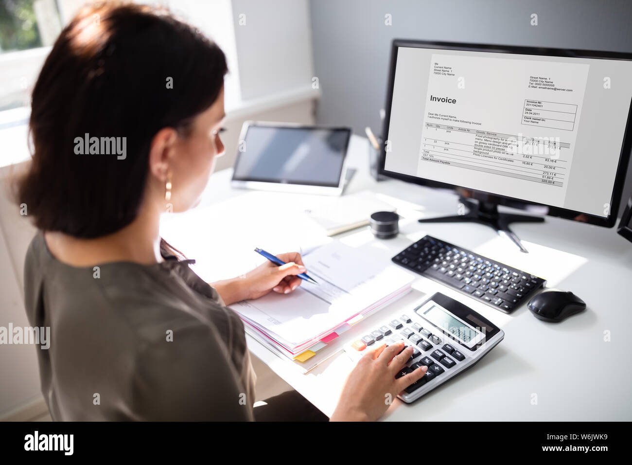 Businesswoman calculating tax at desk in office Stock Photo
