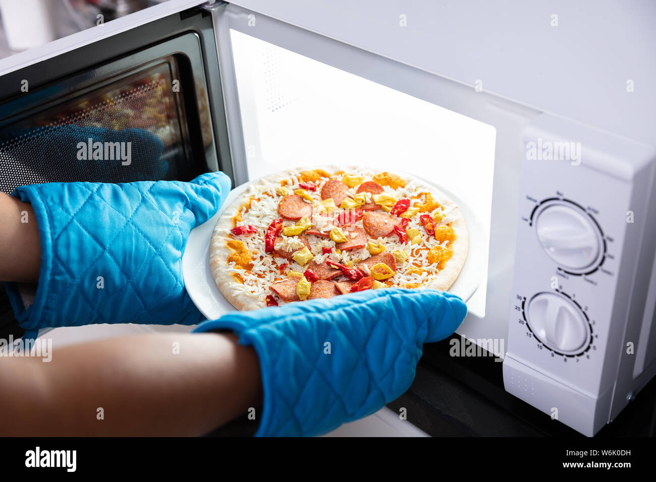 Close-up Of A Happy Woman Baking Pizza In Microwave Oven Stock Photo