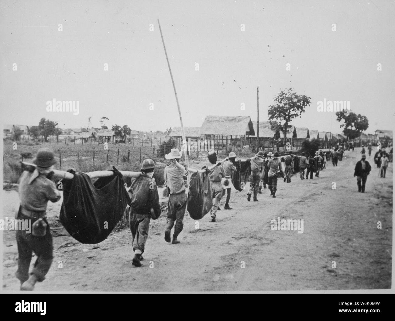Photograph of American Prisoners Using Improvised Litters to Carry Comrades; Scope and content:  Original caption: This picture, captured from the Japanese, shows American prisoners using improvised litters to carry those of their comrades who, from the lack of food or water on the march from Bataan, fell along the road. Philippines, May 1942. General notes:  According to Colonel Melvin H. Rosen (U.S. Army Retired), this image is not a photograph taken during the Bataan Death March, but rather a photograph of a burial detail at Camp O'Donnell, the terminus of the Death March.  Mr. Rosen is a s Stock Photo