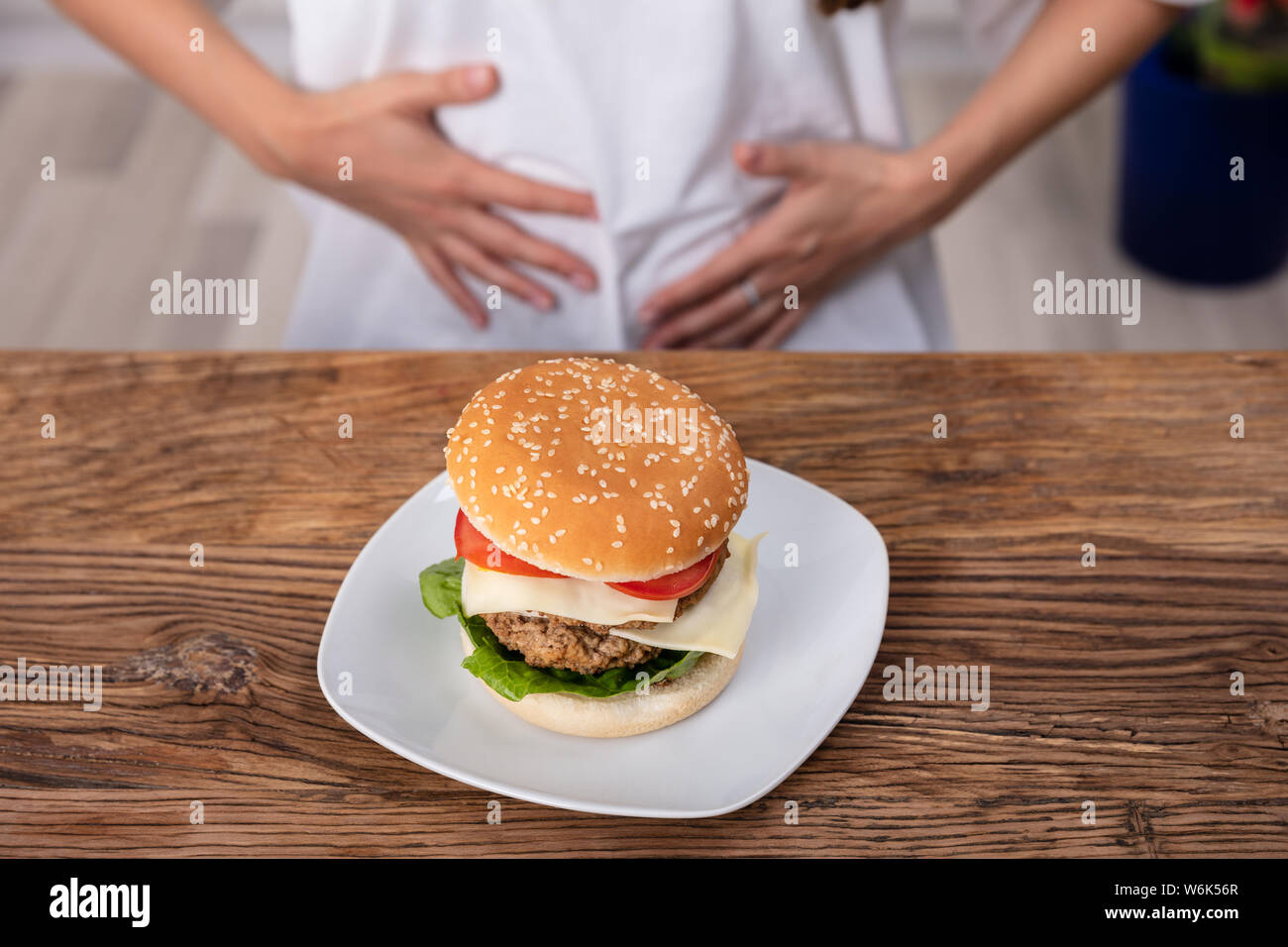 Young Woman Suffering From Stomach Pain While Having Breakfast Stock Photo