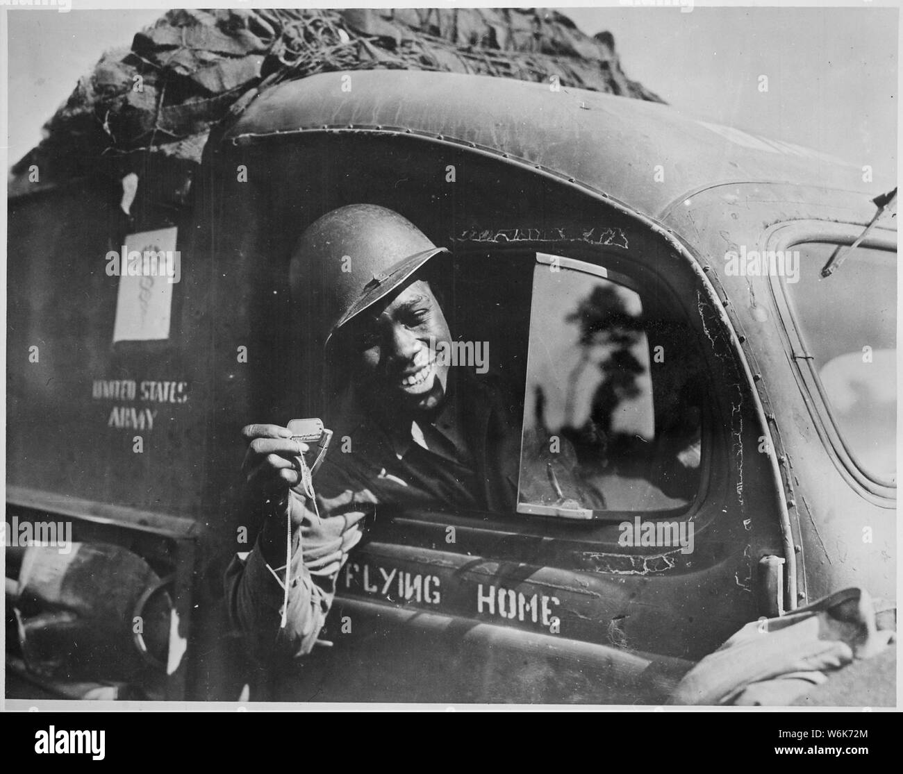 Pvt. William A. Reynolds..., an ambulance driver exhibits a .50-caliber machine gun bullet which lodged above the windshield of his vehicle when he was strafed by a German plane while driving at the front in France..., 1944 Stock Photo