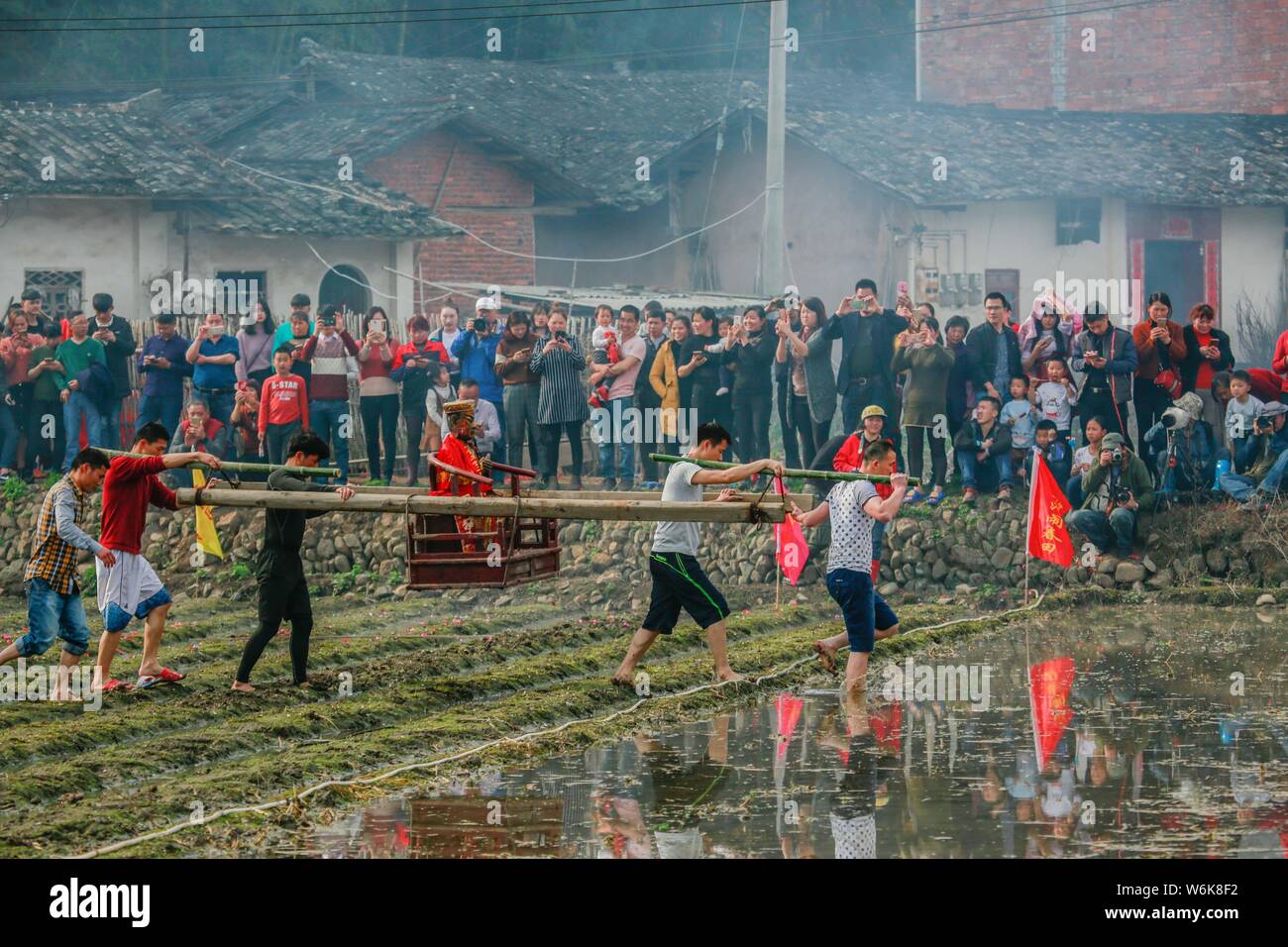 Chinese villagers of the Hakka people carrying a golden statue of ancient  Chinese general Guan Gong dash through waterlogged fields during a  mud-spatt Stock Photo - Alamy, image size:1300x956