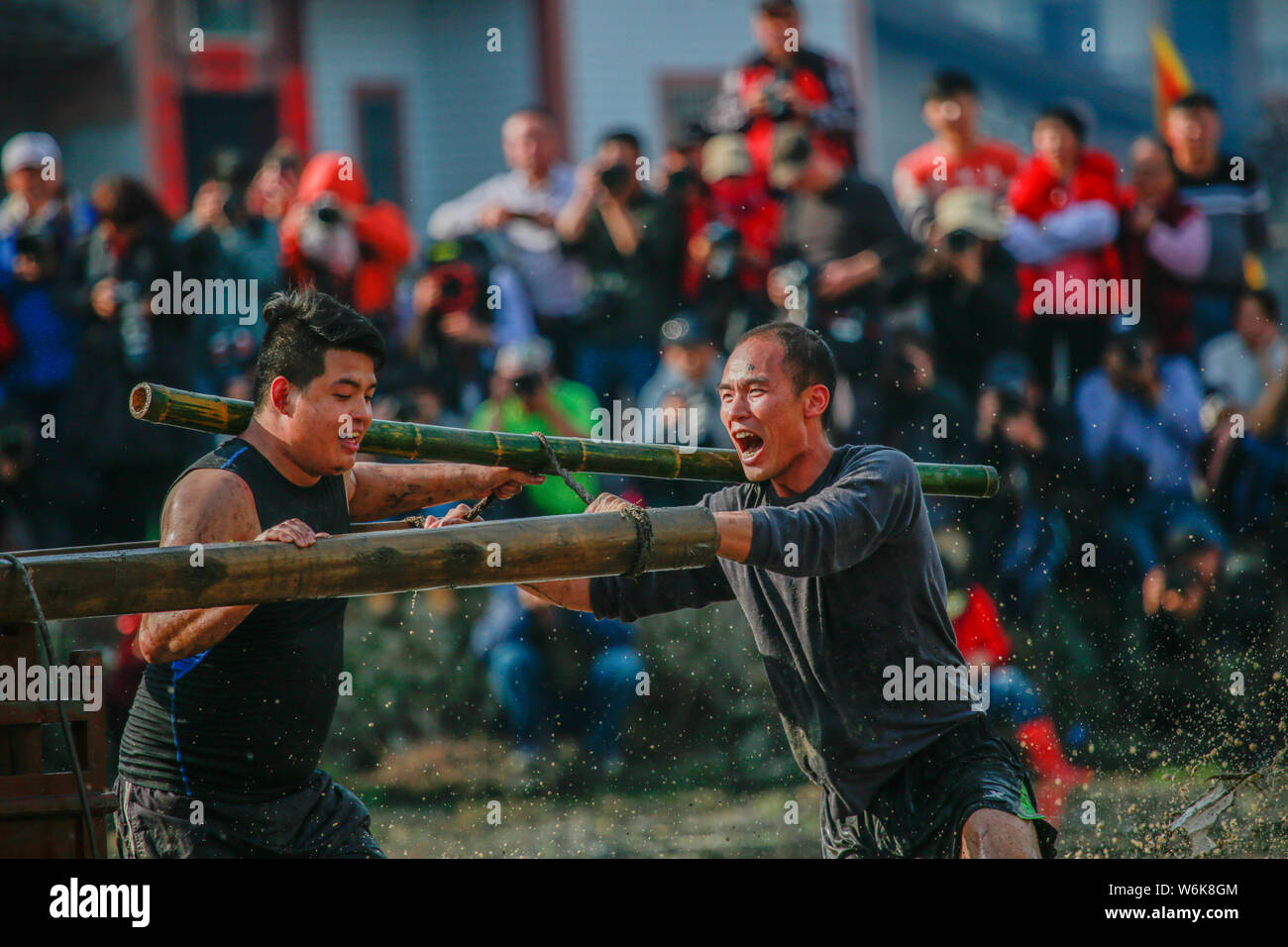 Chinese villagers of the Hakka people carrying a golden statue of ancient Chinese general Guan Gong dash through waterlogged fields during a mud-spatt Stock Photo