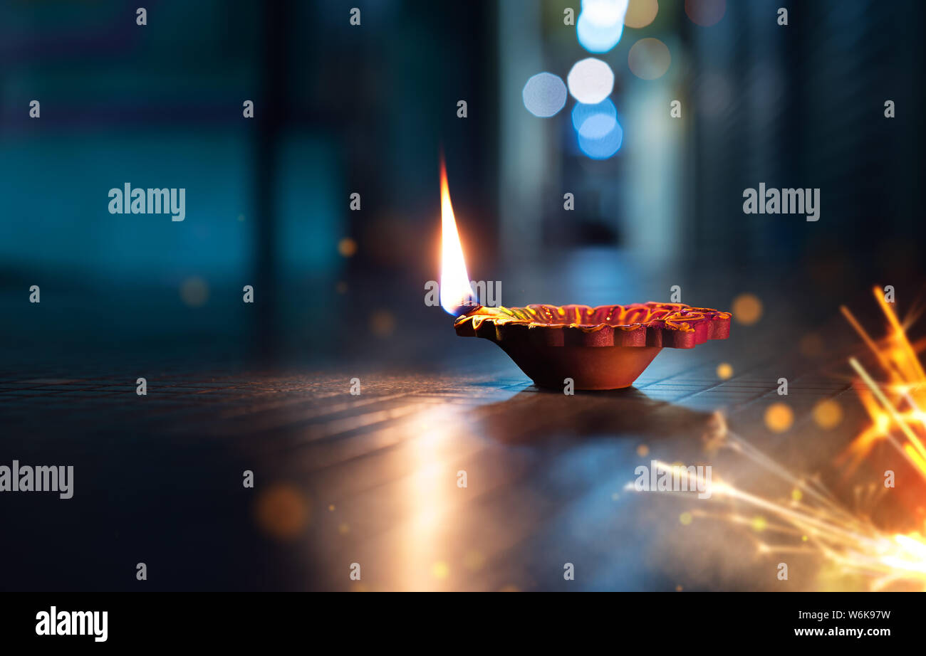 Happy Diwali - Lit diya lamp on street with firecrackers Stock Photo