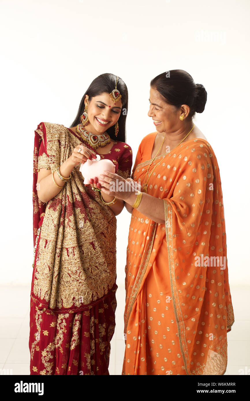 Woman putting coin into a piggy bank with her mother Stock Photo - Alamy