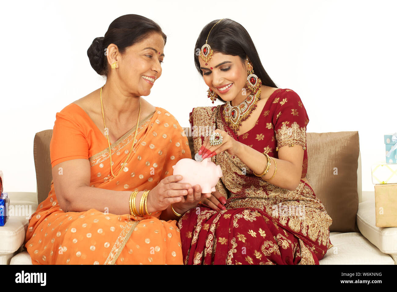 Woman putting coin into a piggy bank with her mother Stock Photo - Alamy