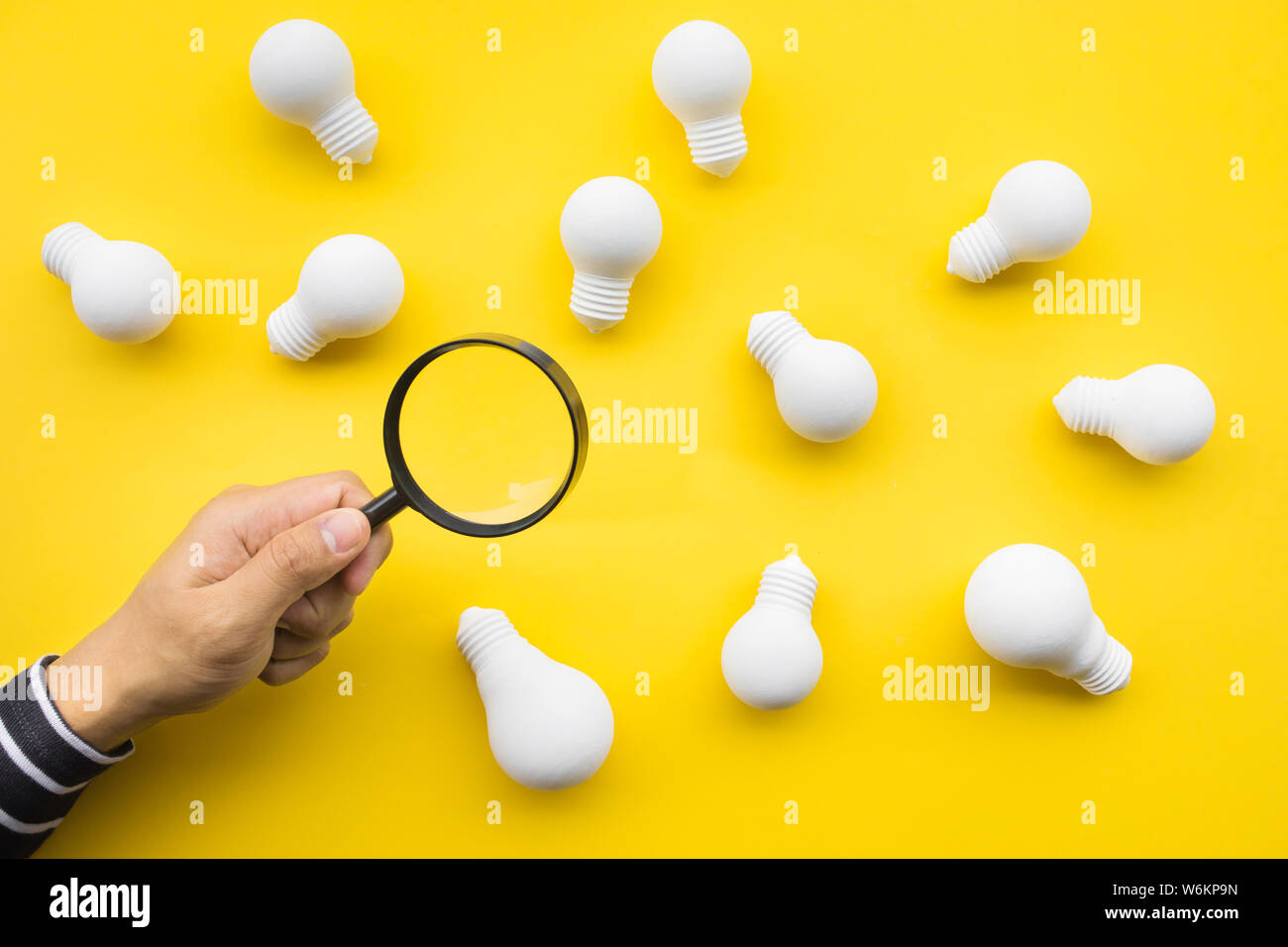 Selected great ideas concepts with male hand using magnifying glass looking for group of lightbulb on color background.Business creativity.human perfo Stock Photo